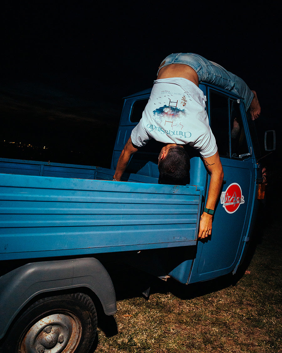 Person doing a handstand in the bed of a blue truck at night.
